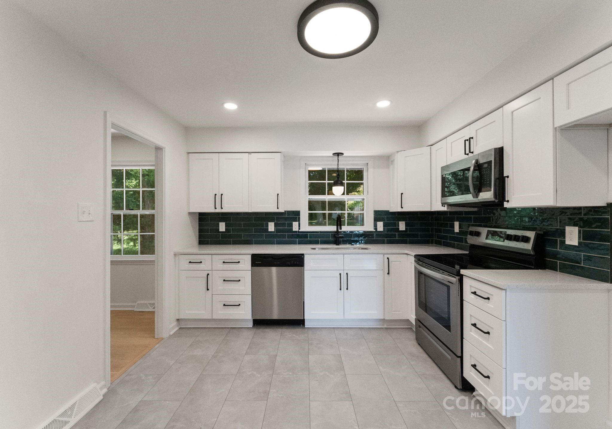 6101 Powder Horn Road Charlotte, NC 28212 - Photo 7 of 27 a kitchen with stainless steel appliances granite countertop a stove top oven a sink a refrigerator and white cabinets
