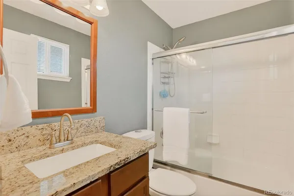 a bathroom with a granite countertop sink toilet and shower