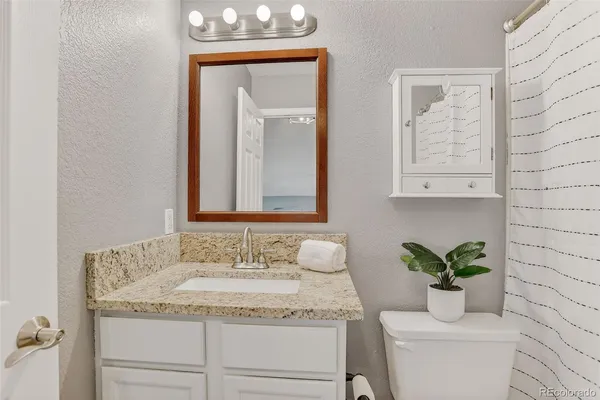a bathroom with a granite countertop sink a toilet and a mirror