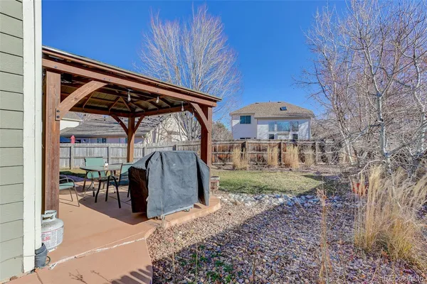 a view of a backyard with table and chairs under an umbrella with a small yard