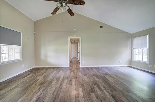 a view of an empty room with window and wooden floor