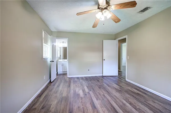 an empty room with wooden floor chandelier and windows