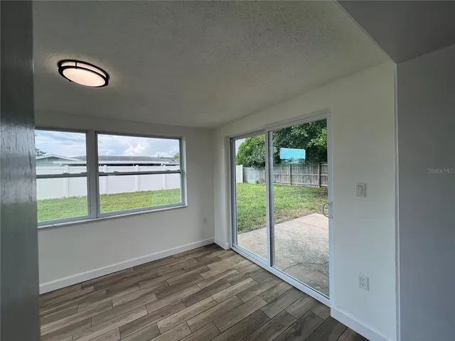 a view of an empty room and wooden floor and windows