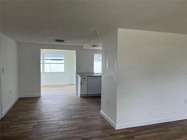 a view of an empty room with a window and wooden floor