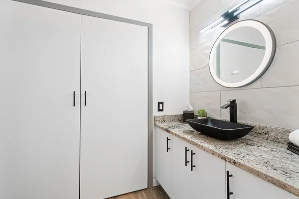 a bathroom with a granite countertop sink a mirror and a shower