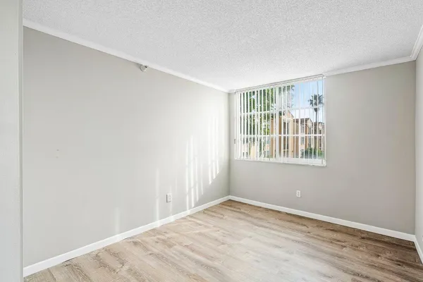 a view of empty room with wooden floor and fan