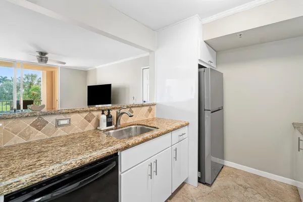 a kitchen with granite countertop a sink and a refrigerator