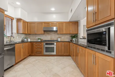 a kitchen with stainless steel appliances granite countertop a refrigerator and a stove top oven