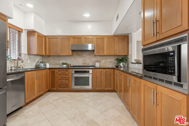 a kitchen with stainless steel appliances granite countertop a refrigerator and a stove top oven