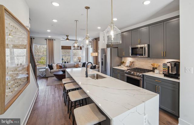 a kitchen with stainless steel appliances kitchen island granite countertop a stove a sink a refrigerator and a wooden floor