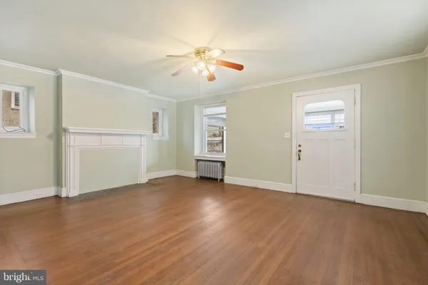 an empty room with wooden floor chandelier fan and windows
