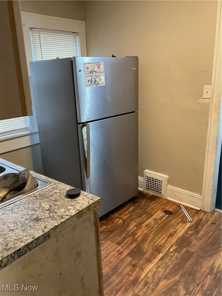 876 Paxton Road Cleveland, OH 44108 - Photo 6 of 26 Kitchen featuring baseboards, visible vents, dark wood-style flooring, freestanding refrigerator, and light countertops