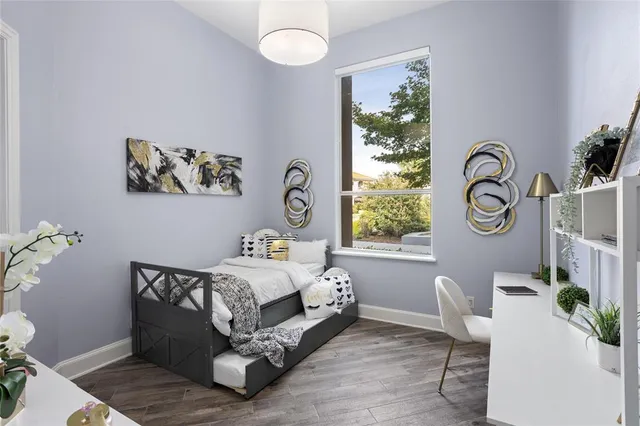 a bed sitting in a bedroom next to a window with a potted plant on a stool