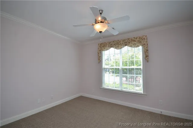an empty room with a chandelier fan and wooden floor