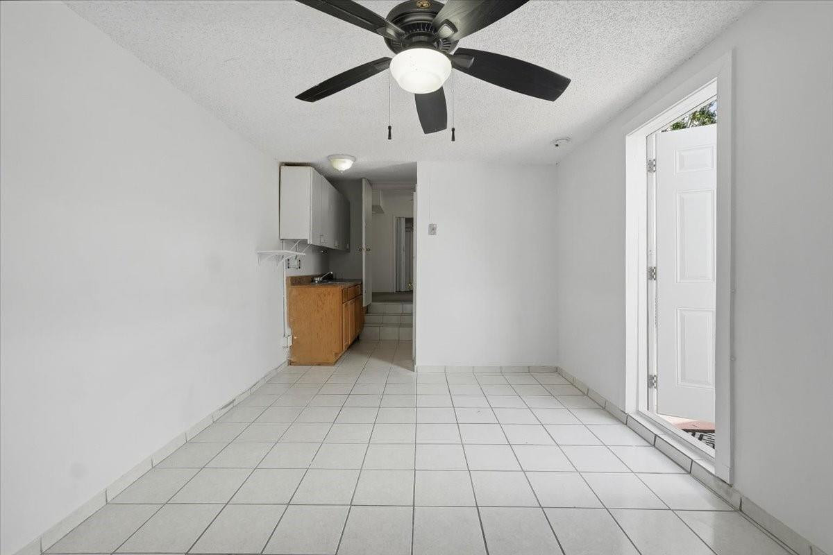 5580 Southwest 2nd Street Miami, FL 33134 - Photo 25 of 29 an empty room with wooden floor ceiling fan and kitchen view