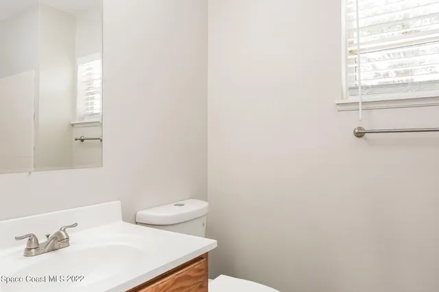 a bathroom with a sink a toilet and a window