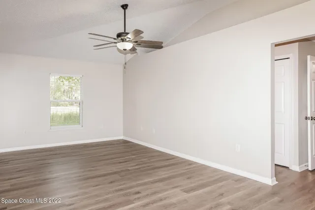 a view of a room with wooden floor a ceiling fan and windows