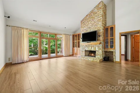 a view of an empty room with fireplace and wooden floor