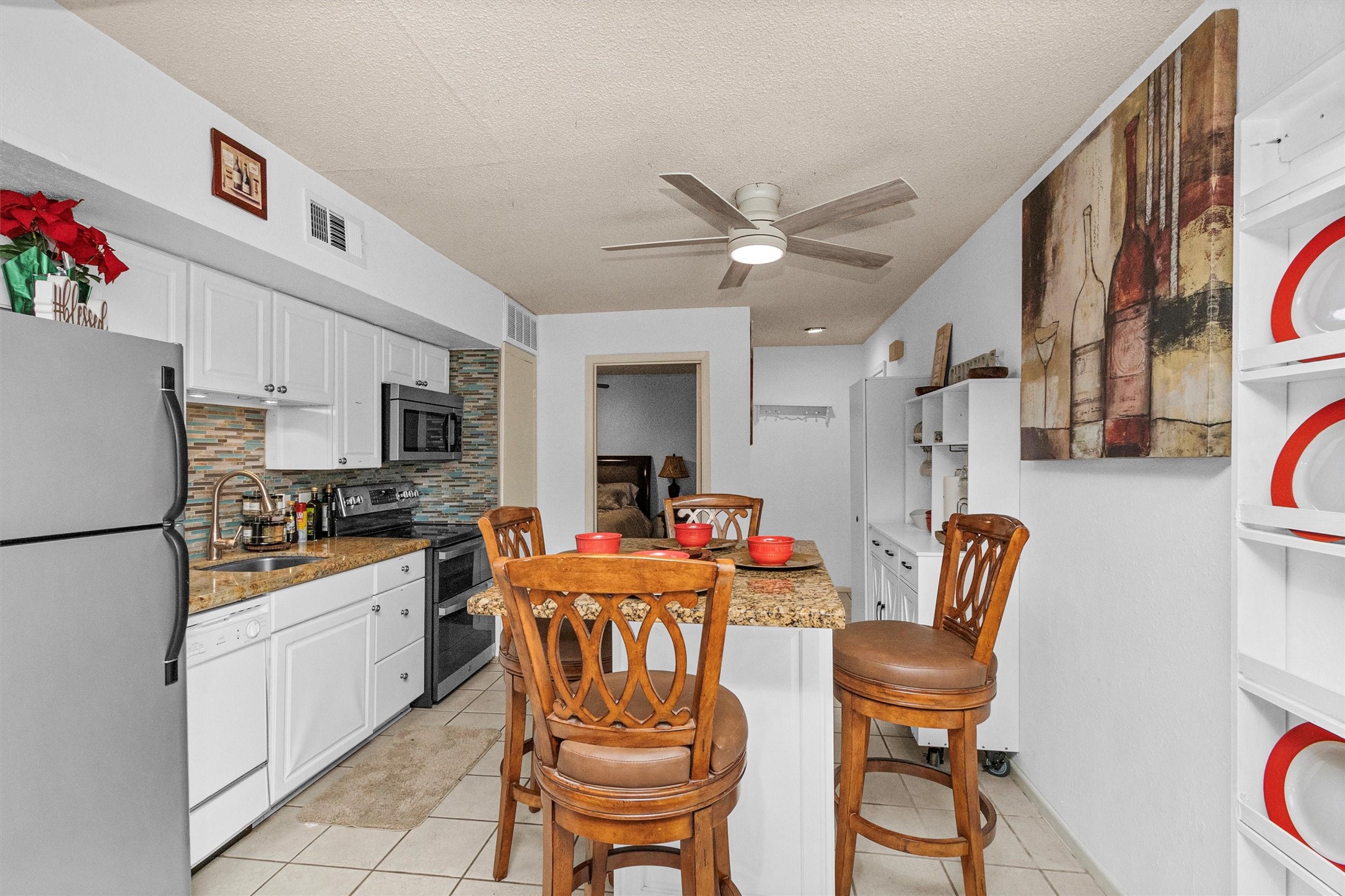 12900 Walden Road, Unit D 411 Montgomery, TX 77356 - Photo 5 of 18 This kitchen offers a warm, inviting ambiance with its open layout, featuring sleek white cabinetry, elegant granite countertops, a chic tile backsplash, modern appliances, and a central island with seating for a perfect blend of style and function.
