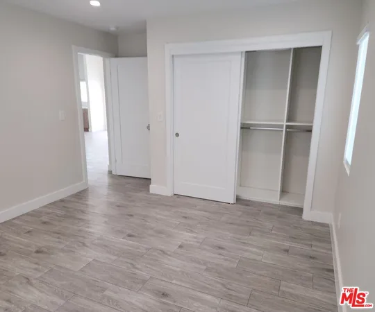 a view of an empty room with wooden floor and closet