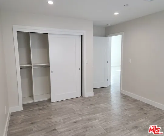 a view of an empty room with wooden floor and closet