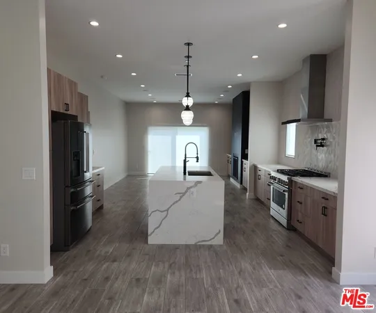 a kitchen with stainless steel appliances granite countertop a refrigerator a stove a sink and a oven