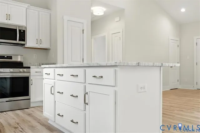 a kitchen with stainless steel appliances granite countertop white cabinets and a stove top oven