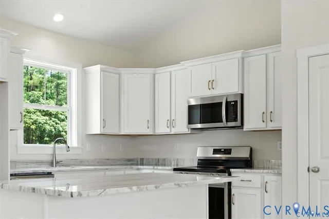 a kitchen with granite countertop white cabinets and a stove