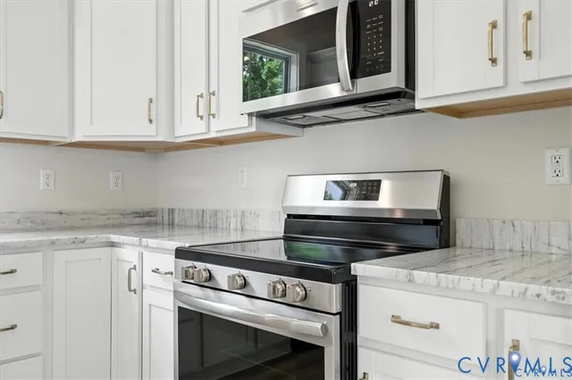 a kitchen with stainless steel appliances a white cabinets and wooden floor