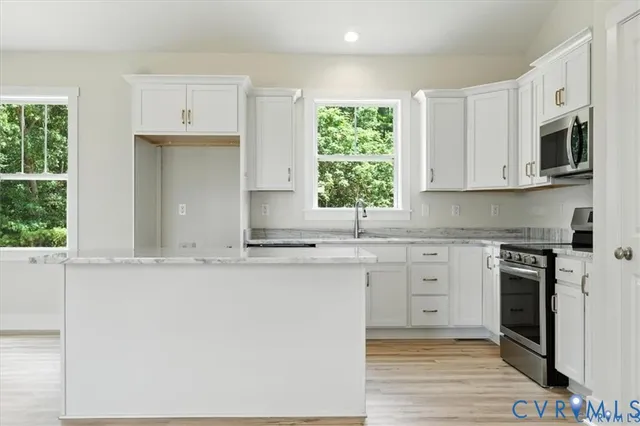 a kitchen with kitchen island granite countertop white cabinets and wooden floor