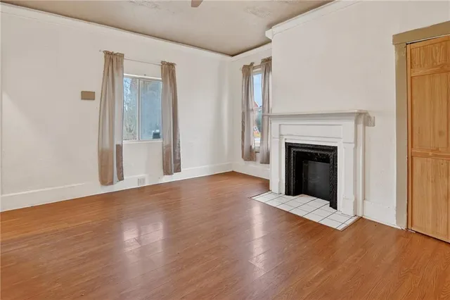 an empty room with wooden floor fireplace and windows