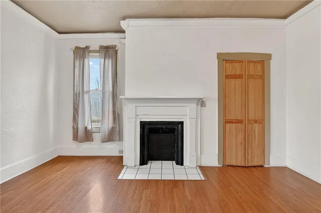 an empty room with wooden floor fireplace and windows