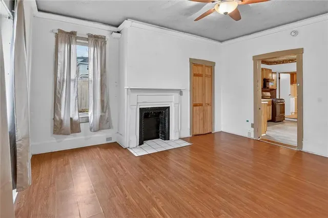 a view of an empty room with wooden floor fireplace and a window