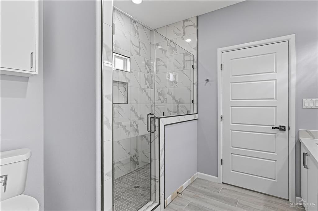 450 Sandy Road Donna, TX 78537 - Photo 12 of 15 Glass-enclosed shower with large format wall tile, built-in shelving, and a mosaic tile floor