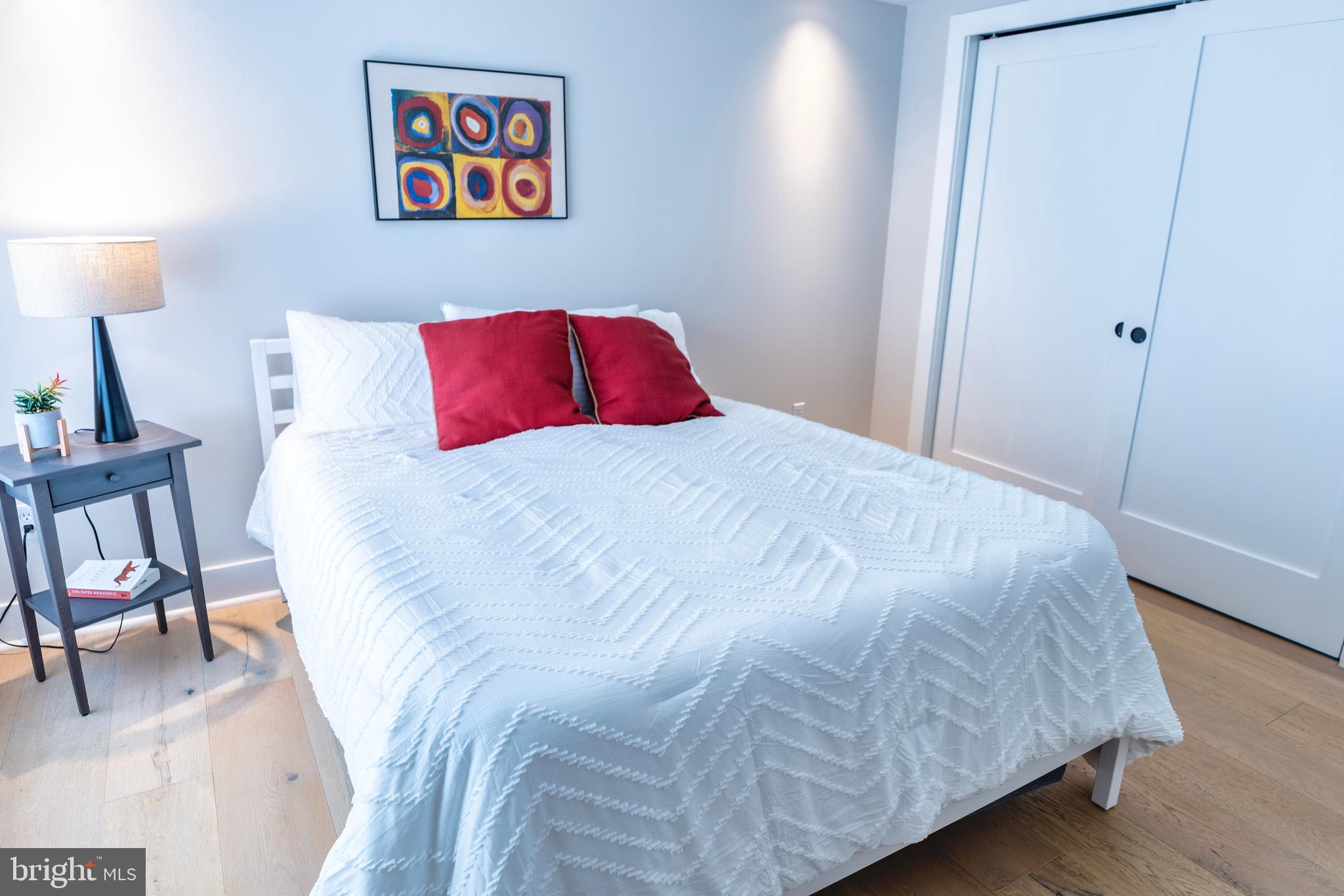 919 12th Street Northeast, Unit 202 Washington, DC 20002 - Photo 15 of 32 a large white bed in a bedroom next to a lamp