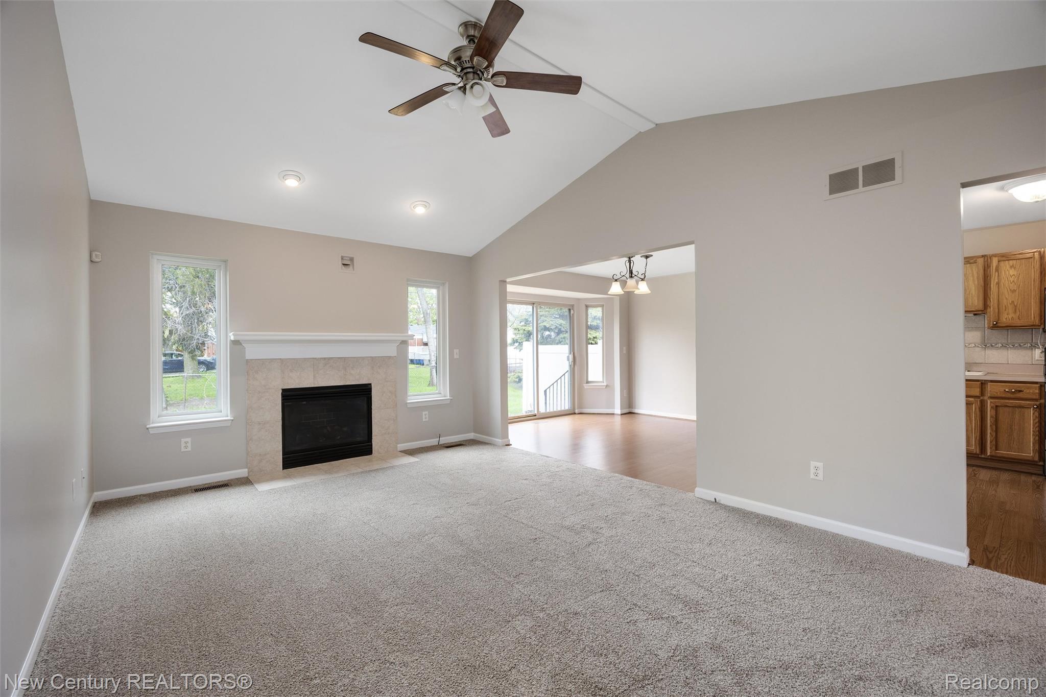 26013 Ranger Avenue Warren, MI 48091 - Photo 3 of 25 Unfurnished living room featuring a ceiling fan, a tiled fireplace, carpet flooring, a high ceiling, and a chandelier