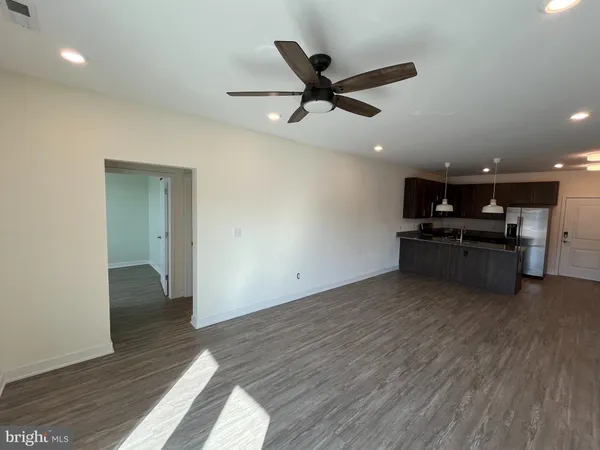 an empty room with wooden floor a ceiling fan and windows