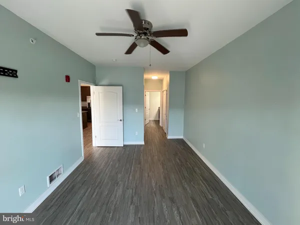 a view of empty room with wooden floor and fan