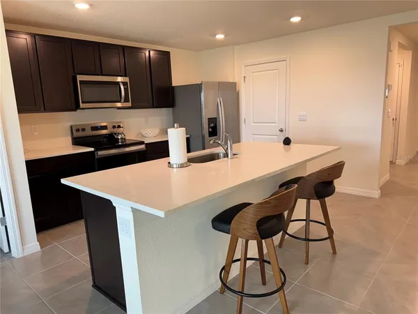 a kitchen with stainless steel appliances a table chairs refrigerator and microwave