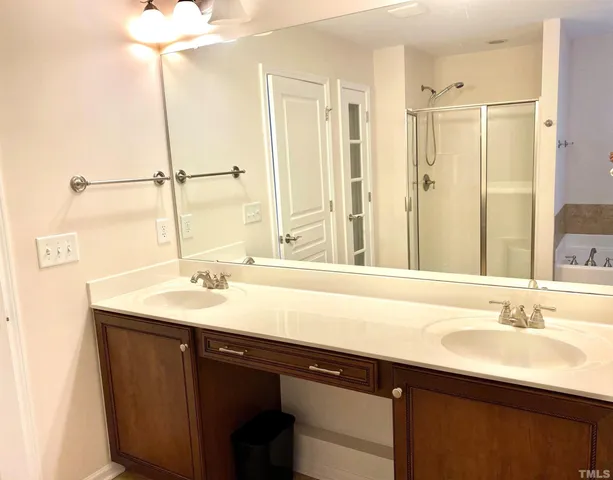a bathroom with a sink double vanity granite tub shower and a mirror
