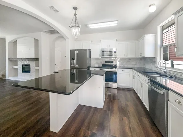 a kitchen with kitchen island granite countertop a sink a counter space stainless steel appliances and cabinets