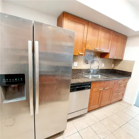 a kitchen with granite countertop a refrigerator a stove a sink and dishwasher