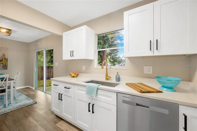 a kitchen with a sink a stove and white cabinets with wooden floor