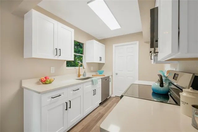 a kitchen with stainless steel appliances a white stove top oven and white cabinets