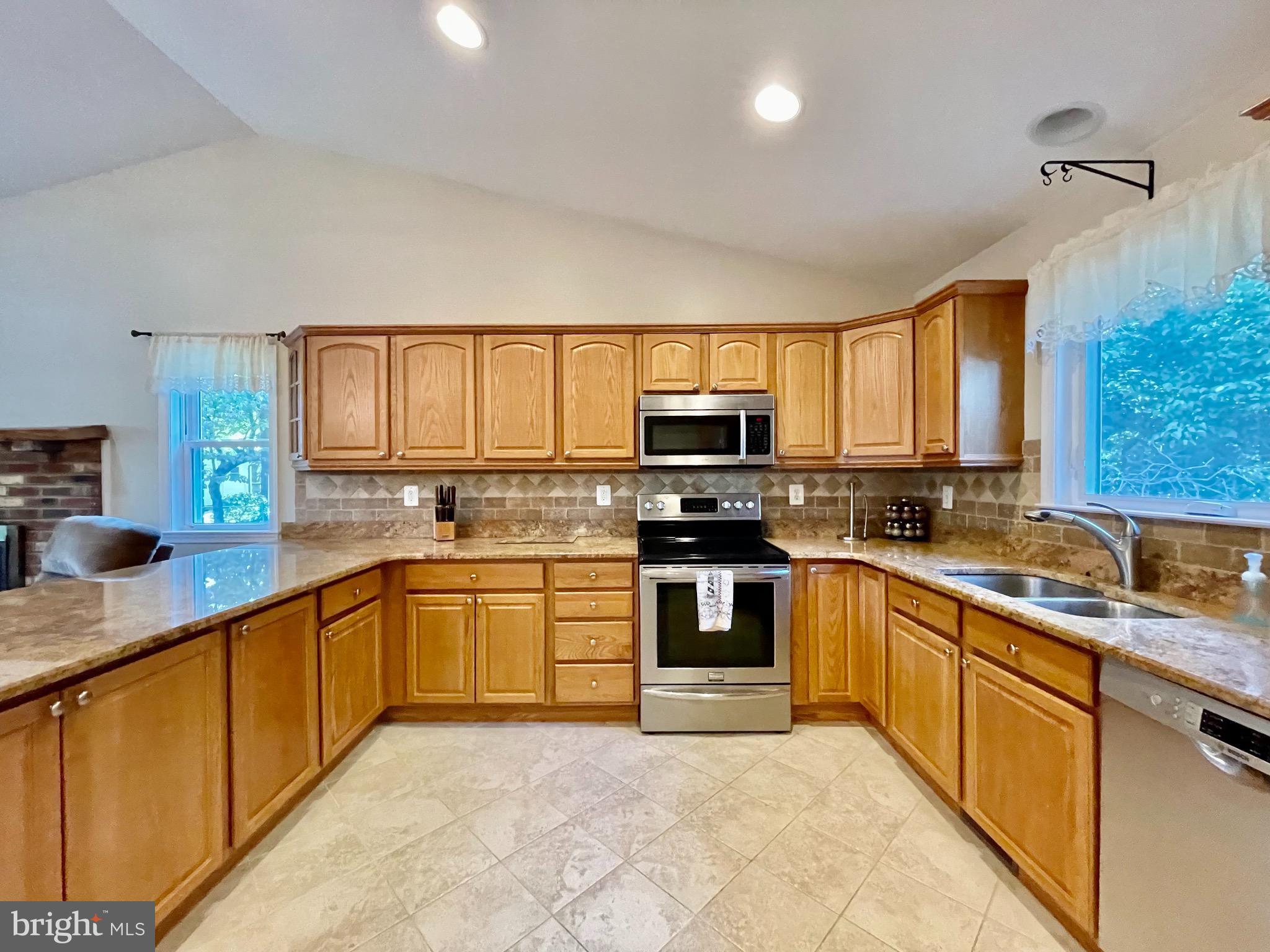 1270 Calvert Beach Road St. Leonard, MD 20685 - Photo 8 of 31 a large kitchen with stainless steel appliances granite countertop a stove top oven a sink dishwasher a dining table and chairs with wooden floor