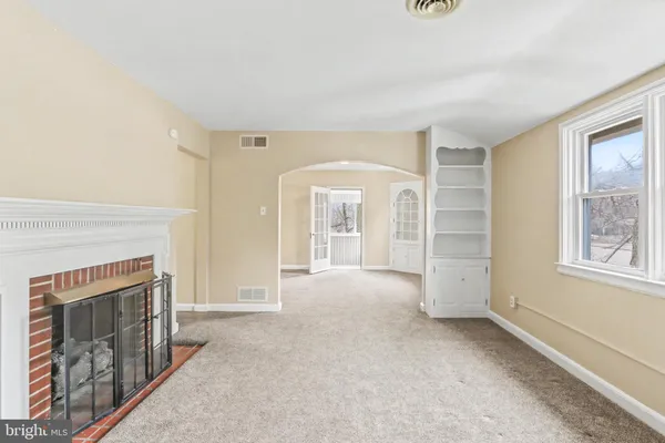 an empty room with windows and fireplace