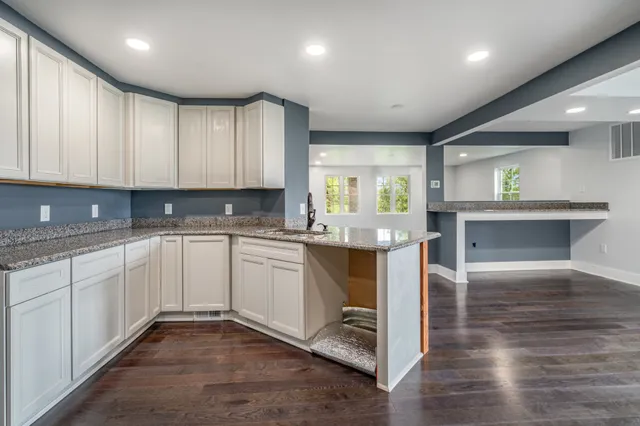a kitchen with granite countertop cabinets stainless steel appliances a sink and a window