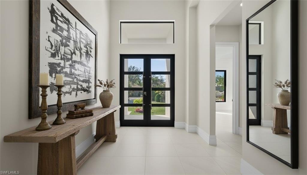 1045 Morningside Drive Naples, FL 34103 - Photo 12 of 50 Virtually Staged Doorway to outside featuring tile patterned floors, a towering ceiling, and french doors