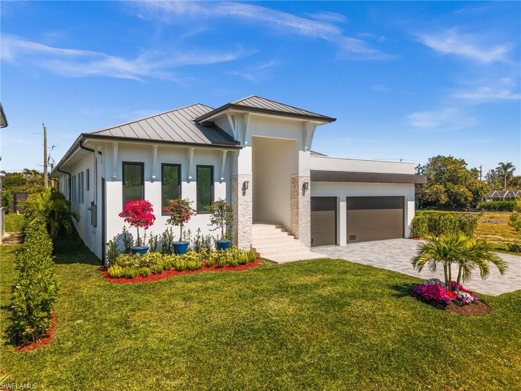 1045 Morningside Drive Naples, FL 34103 - Photo 2 of 50 View of front facade featuring a standing seam roof, a metal roof, a garage, and a front lawn