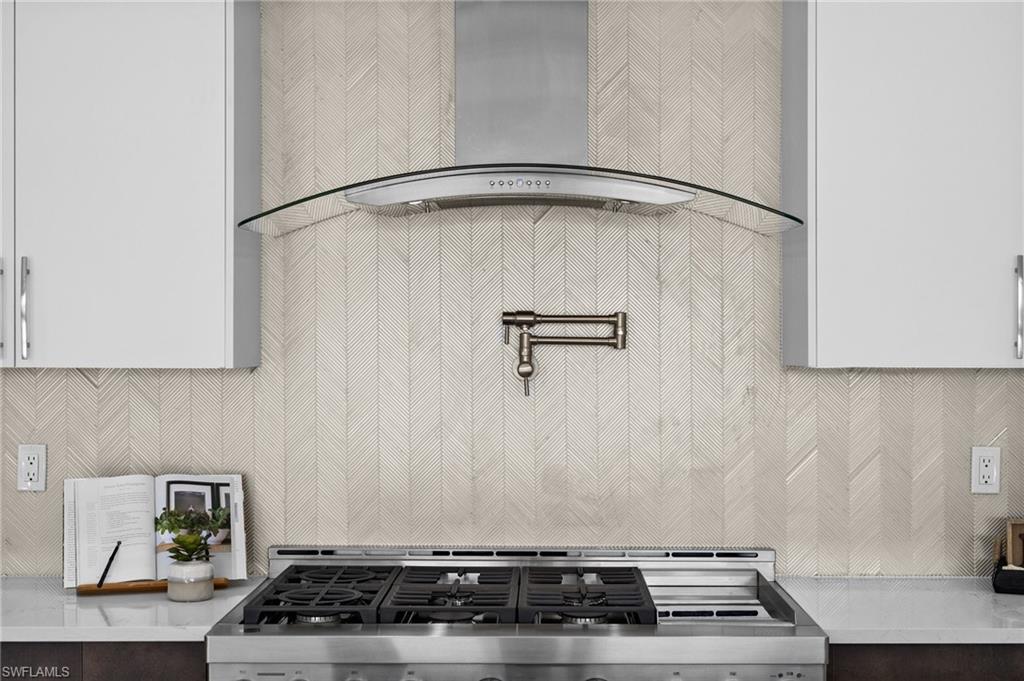 1045 Morningside Drive Naples, FL 34103 - Photo 6 of 50 Kitchen view of wall chimney exhaust hood, backsplash, pot filler, light stone counters, and stainless steel gas stove